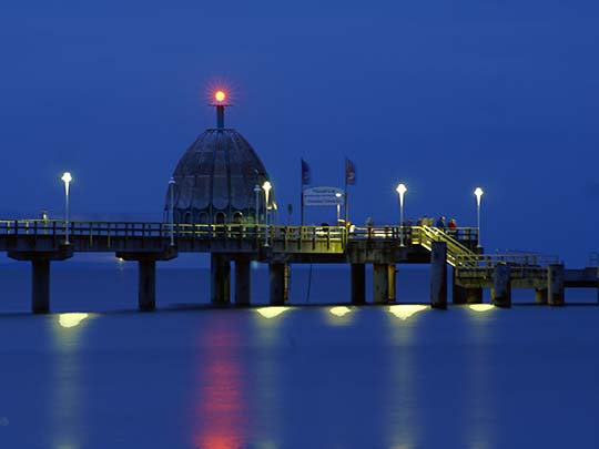 Die beleuchtete Seebrücke Zinnowitz mit Tauchgondel in der Dunkelheit am Abend